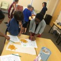 Emilola Abayomi, Ph.D., (shown at front table) assistant professor at the Halmos College of Natural Sciences and Oceanography, works with children at a STEM Programs for Children session presented by college faculty and students at the Alvin Sherman Library.