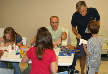 Pop-up book creator Chuck Fischer (seated) and children’s book illustrator Henry Cole (standing) instruct children with their projects.