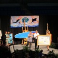 Auctioneer Harry Stampler, Guy Harvey and Mellanie Tillbrook with Guy Harvey original during live auction.