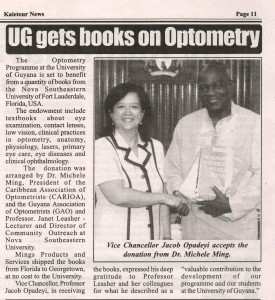 UG Vice Chancellor Prof Jacob Opadeyi and Michele Ming shake hands as he displays some of the books donated to the university