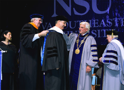 Ralph Rogers, Ph.D., Nova Southeastern University provost and executive vice president for academic affairs; hoods U.S. Rep. Diaz-Balart at NSU Health Professions Division Commencement alongside George L. Hanbury II, Ph.D., NSU president; following the presentation of an Honorary Degree Citation, with Jacqueline Travisano (far left), M.B.A., C.P.A., NSU executive vice president and chief operating officer, and Fred Lippman (far right), R.Ph., Ed.D., chancellor of NSU’s Health Professions Division