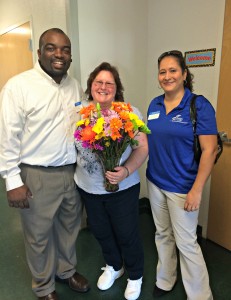 Michael Daniels, Orlando campus director and Christina Ortiz, operations administrator recognize alumni, Susan Deck with flowers and wishes of congratulations on her first day of school.  