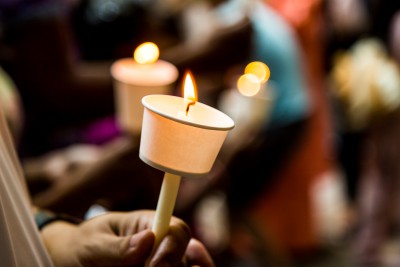 Closeup of people holding candle vigil in darkness expressing and seeking hope